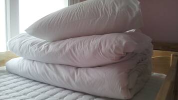A stack of white pillows on a bed with a quilted cover.