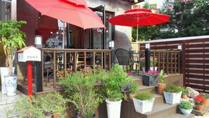 Ein Café mit Außenbereich, roten Sonnenschirmen und Blumentöpfen.