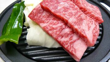 A black grill pan with slices of pink meat and white vegetables.