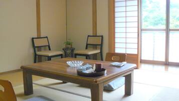A traditional Japanese room with tatami flooring, a low wooden table, and two chairs.