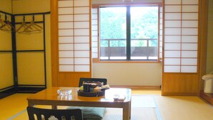 Una habitación japonesa tradicional con suelo de tatami, una mesa baja, una silla y una puerta corredera estilo shoji.