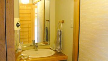 A bathroom with a wooden vanity, a sink, a mirror, a towel rack, and a bottle of hand soap.