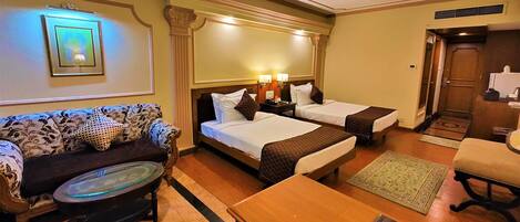 A hotel room with two beds, a sofa, a coffee table, and a small table with a magazine.