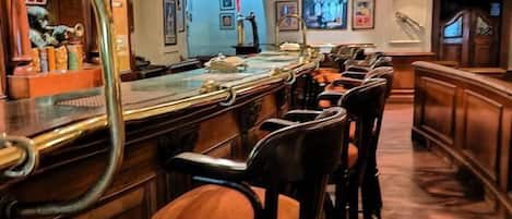 Un espace bar doté d’un long comptoir, de plusieurs tabourets et d’un miroir décoratif.