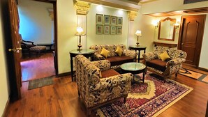 A traditional living room with patterned sofas, a coffee table, and a decorative rug. - Tuli International (Nagpur)