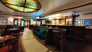A bar area with a stained glass ceiling, wooden bar counter, and seating arrangements. - Tuli International (Nagpur)