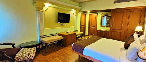A hotel room with a bed, desk, chair, and a television on the wall.