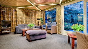 A cozy living room with a television, sofa, ottoman, and wicker chairs. - Owl Hotel (Amsterdam)