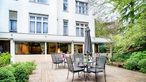 A patio area with outdoor seating, a covered section, and a building with large windows. - Owl Hotel (Amsterdam)
