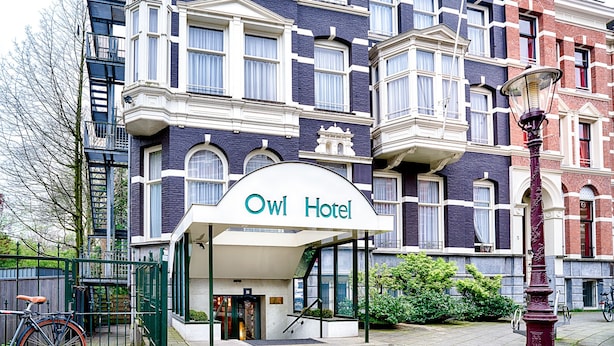 The exterior of the Owl Hotel with a prominent entrance, a bicycle parked outside, and a street lamp nearby. - Owl Hotel (Amsterdam)