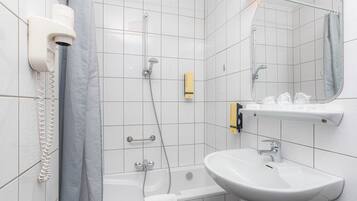 A modern bathroom with a white sink, a mirror, a shower, and a hairdryer mounted on the wall.