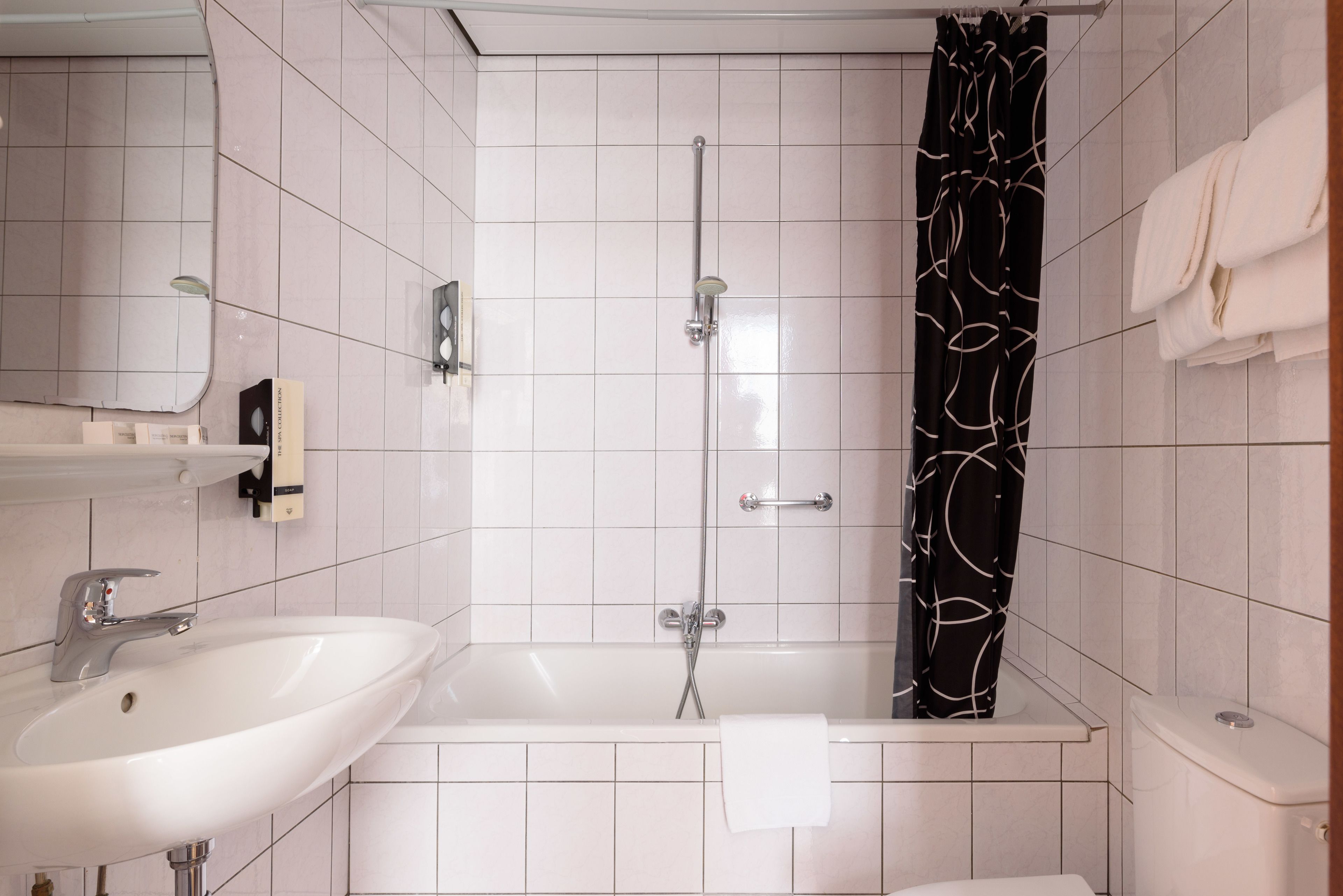 Et badeværelse med vask, badekar og bruser.