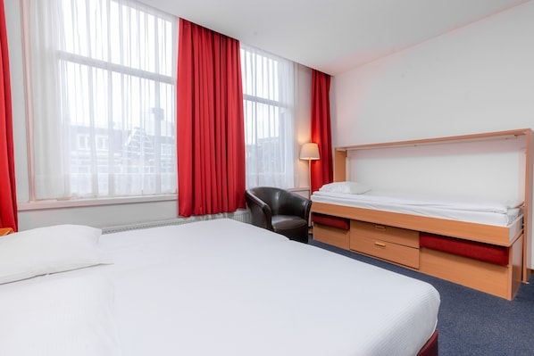 A hotel room with a large bed, a desk, and a chair.