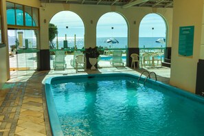 Una piscina techada, una piscina al aire libre, sombrillas