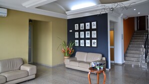 En lobby med en beige sofa, en potteplante, indrammet kunst på væggen og en trappe i baggrunden.