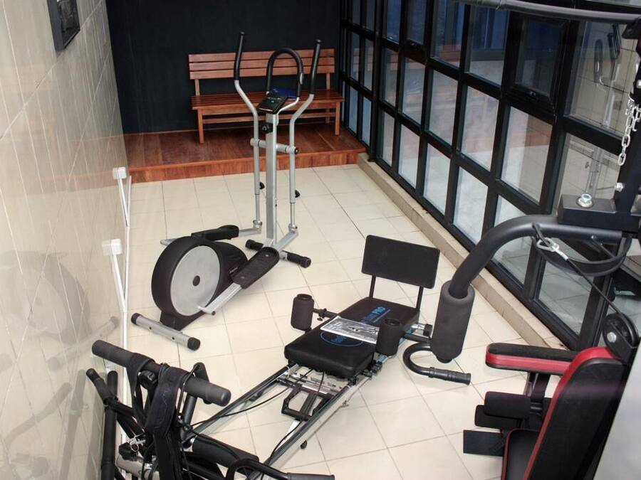 A gym with exercise equipment, a bench, and large windows.