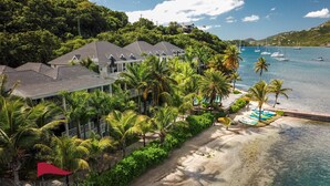 A beachfront hotel with multiple buildings, palm trees, and boats in the water. - South Point Antigua Ocean Suites (English Harbour)