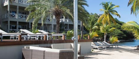 A beachside shower with a view of a resort building and palm trees.