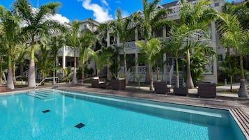 Relax by the pool surrounded by palm trees and wicker lounge chairs.