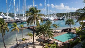 A marina with multiple sailboats docked, a swimming pool, and palm trees. - South Point Antigua Ocean Suites (English Harbour)