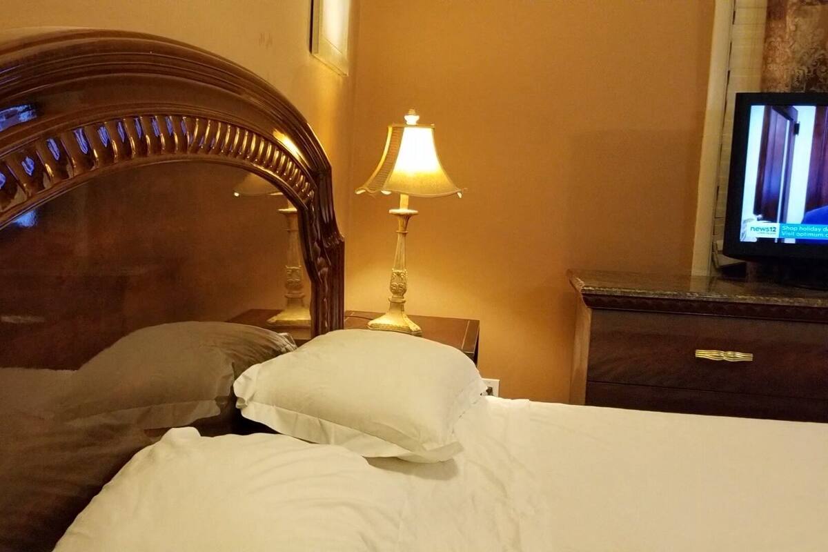 Een hotelkamer met een houten hoofdbord, een bedlamp, een televisie en een nachtkastje.