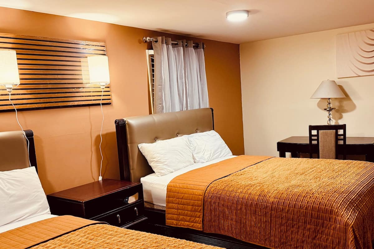 Een hotelkamer met twee bedden, een nachtkastje met lamp, een spiegel aan de muur en een schilderij.