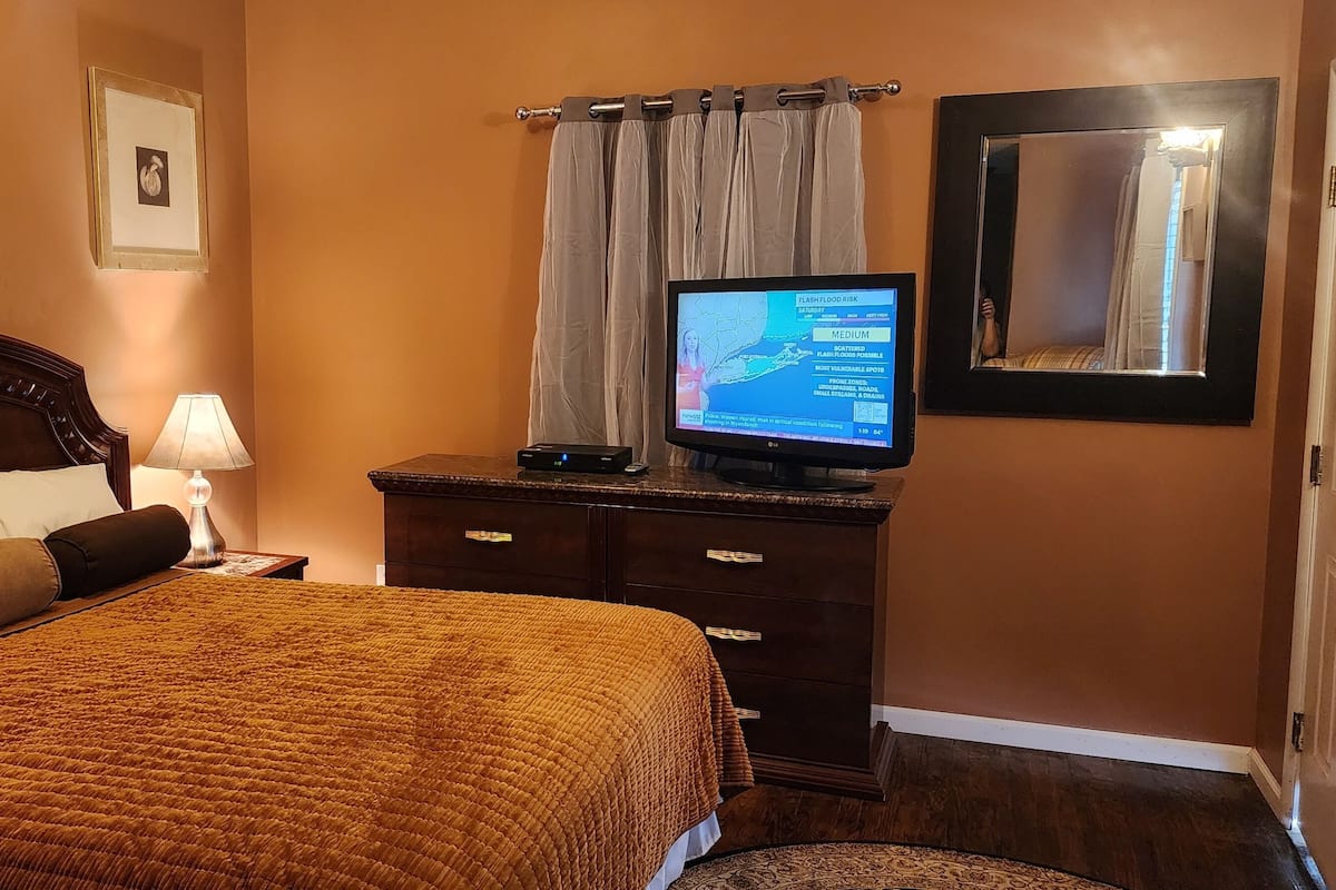 Een hotelkamer met een bed, een televisie, een dressoir en een spiegel.