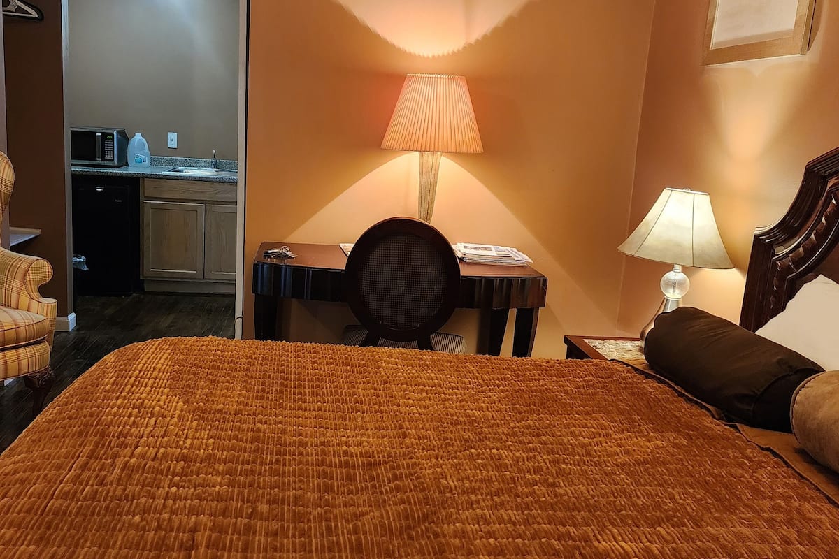 Een hotelkamer met een groot bed, een stoel, een bureau en een lamp.