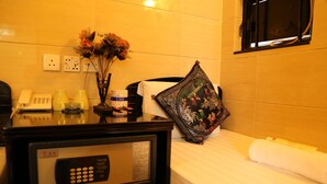 A hotel room with a bed, a bedside table with a phone, a vase with flowers, and a decorative pillow. - New Tokyo Hostel (Kowloon)