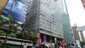 A multi-story building with large advertisements on its facade, including one for a youth activating program. - New Tokyo Hostel (Kowloon)