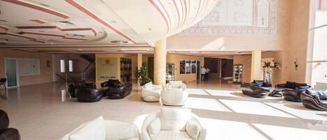 A spacious lobby with a high ceiling, modern seating areas, and a staircase leading to upper floors.