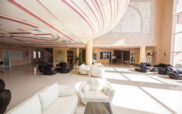 A spacious lobby with a high ceiling, modern seating areas, and a staircase leading to upper floors.