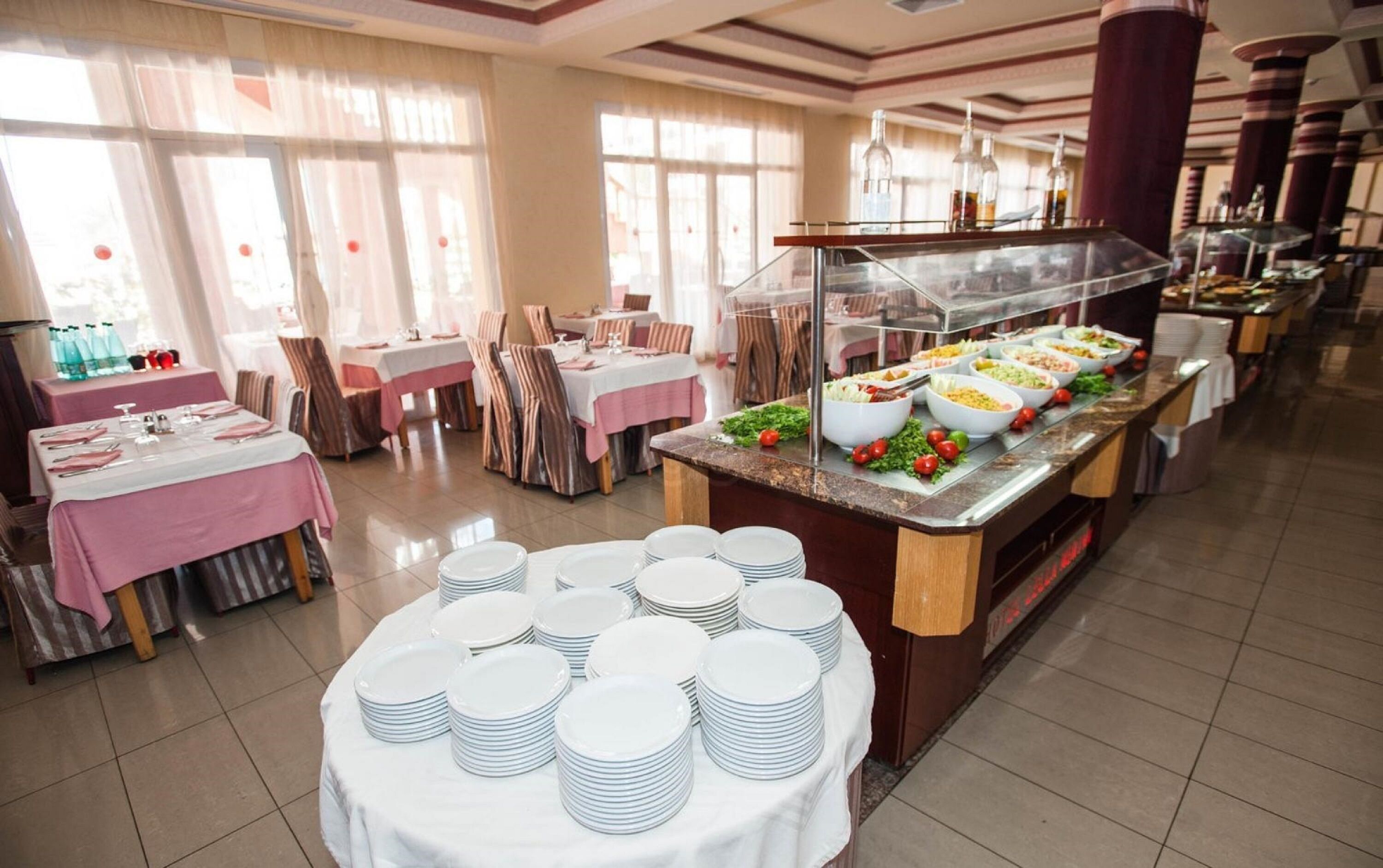 Un buffet avec plusieurs présentoirs de nourriture et un espace repas comprenant des tables et des chaises.