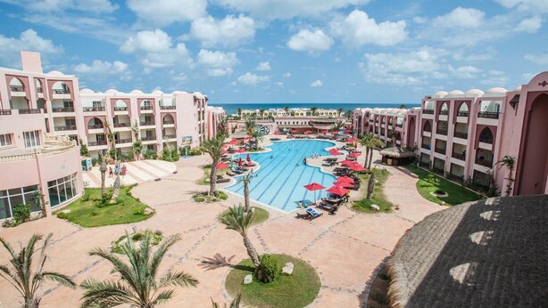 Un resort con piscina central, varios balcones y vistas al océano.