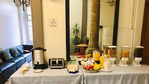 A breakfast buffet setup with a coffee maker, toaster, and various food items including fruits and cereal. - Hostel Lit (Guadalajara)