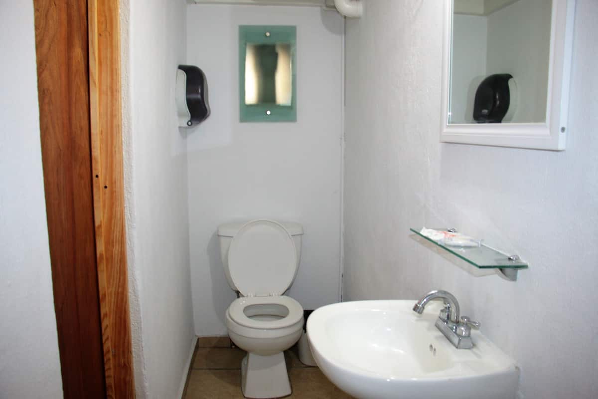 A small bathroom with a toilet, sink, and a mirror.