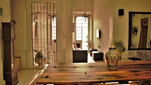 A spacious living room with a wooden table, a decorative vase, and a large window allowing natural light. - Hostel Lit (Guadalajara)