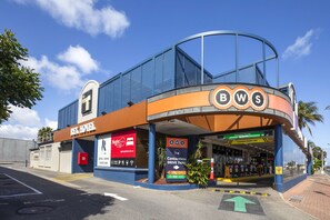 A hotel with a curved facade, a prominent BWS sign, and a contactless drive-thru service.