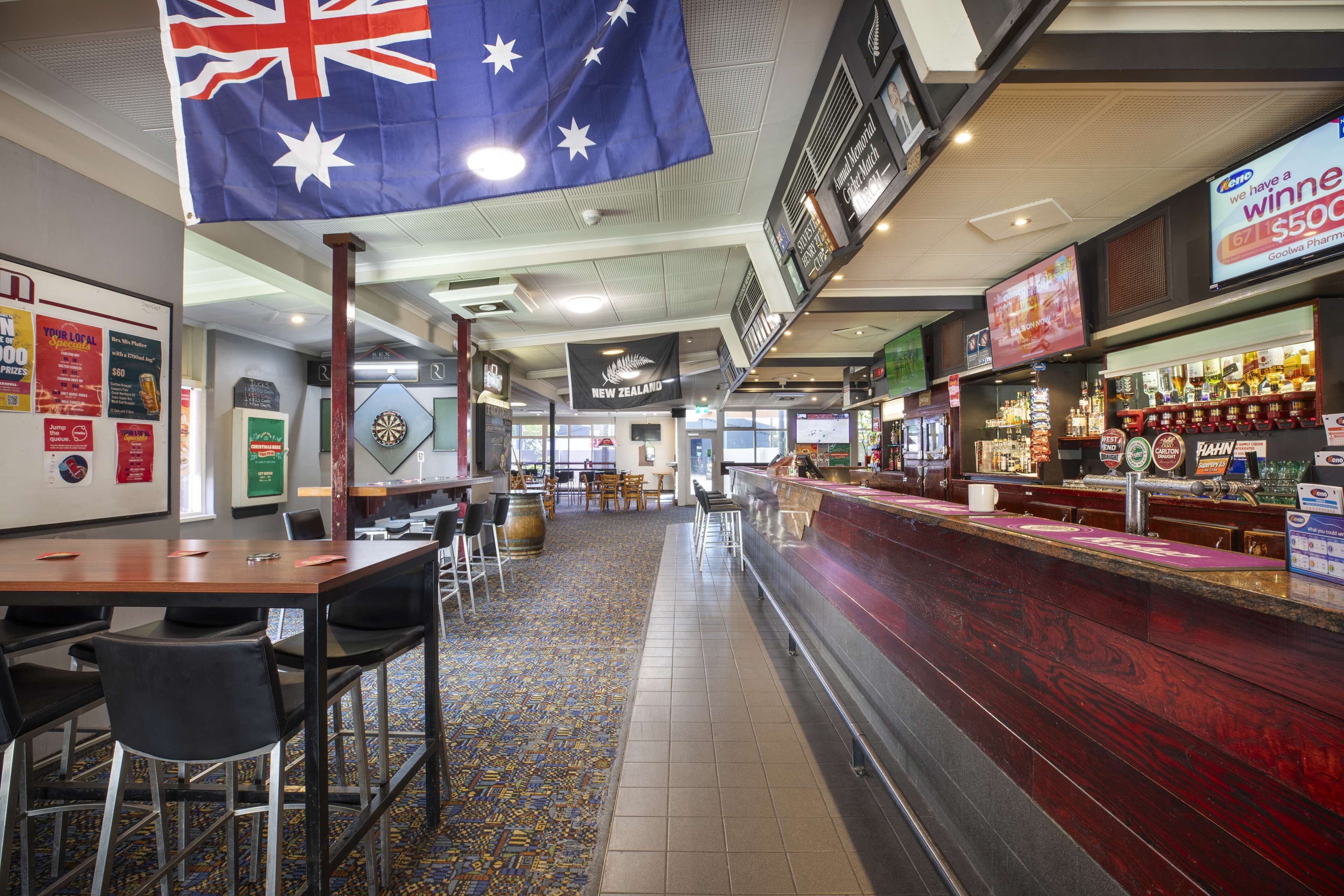 A restaurant with a bar area, tables, chairs, and a New Zealand flag.