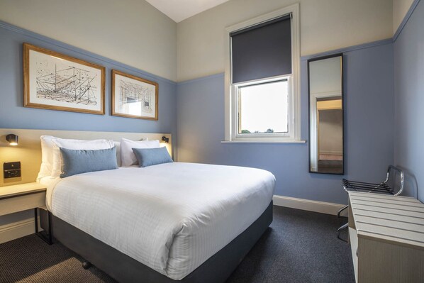 A hotel room with a large bed, two bedside tables, a desk, a mirror, and two framed pictures on the wall. - Nightcap at Rex Hotel (Marleston)
