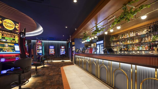 A bar area with slot machines, a bar counter, and seating. - Nightcap at Rex Hotel (Marleston)