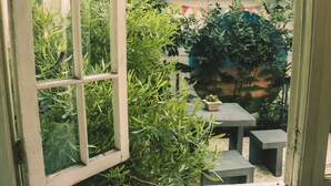 A view through a window into a small, enclosed garden area with a concrete table and bench. - Hostal Providencia - Hostel (Santiago)