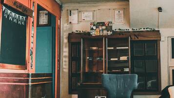 A cozy living room with a wooden coffee table, a blue armchair, and a bookshelf filled with books and decorative items.