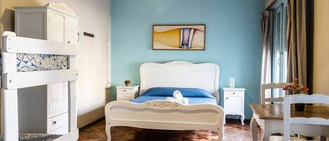 Un dormitorio con cama, literas, mesita de noche, silla y un cuadro en la pared.