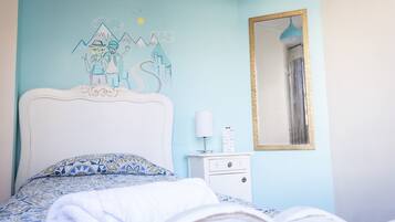 A bedroom with a bed, a nightstand, a mirror, and a wall mural.