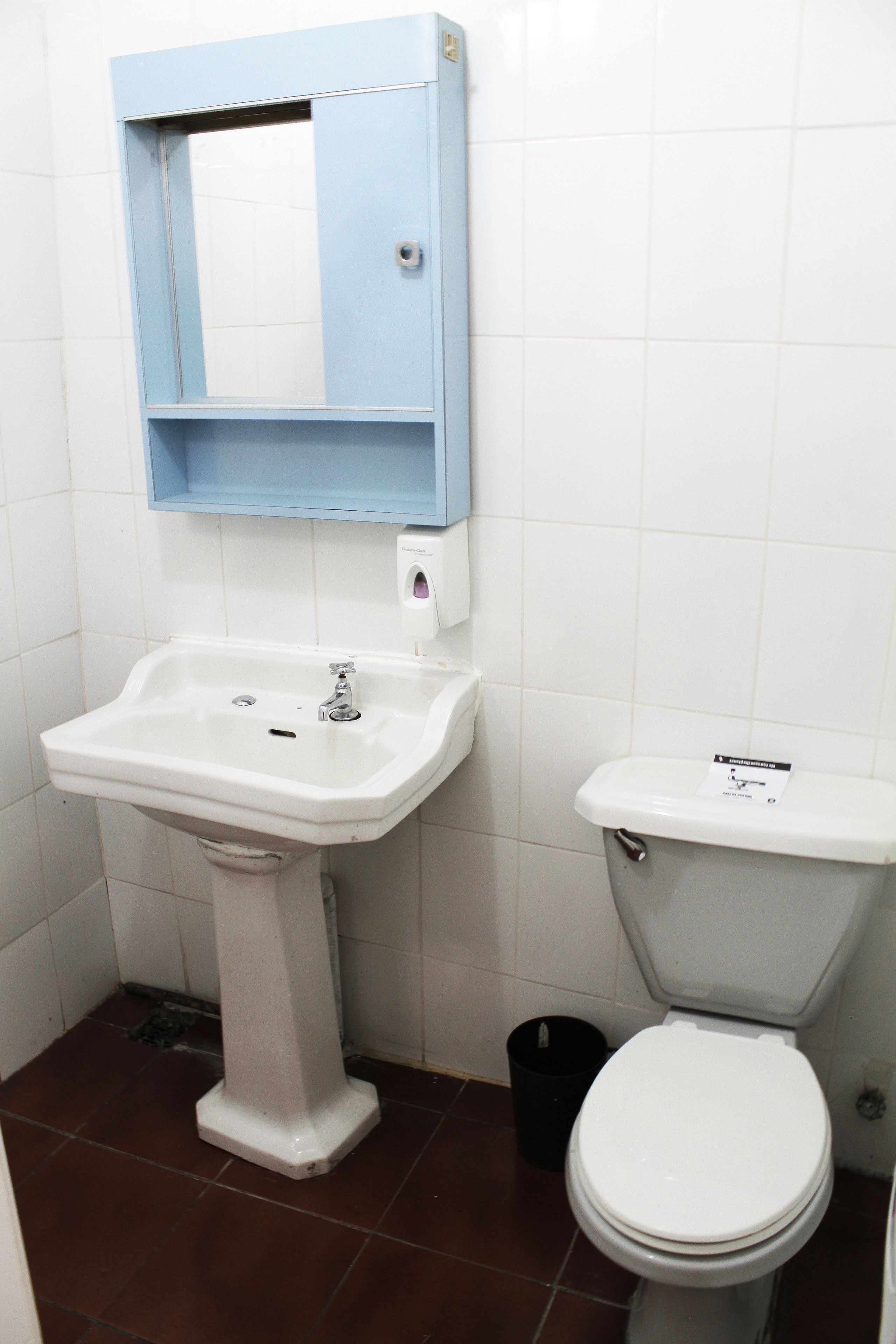 A bathroom with a pedestal sink, a toilet, and a blue medicine cabinet.