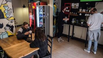 Un café con un refrigerador de Coca-Cola, una zona de bar y un mural en la pared.
