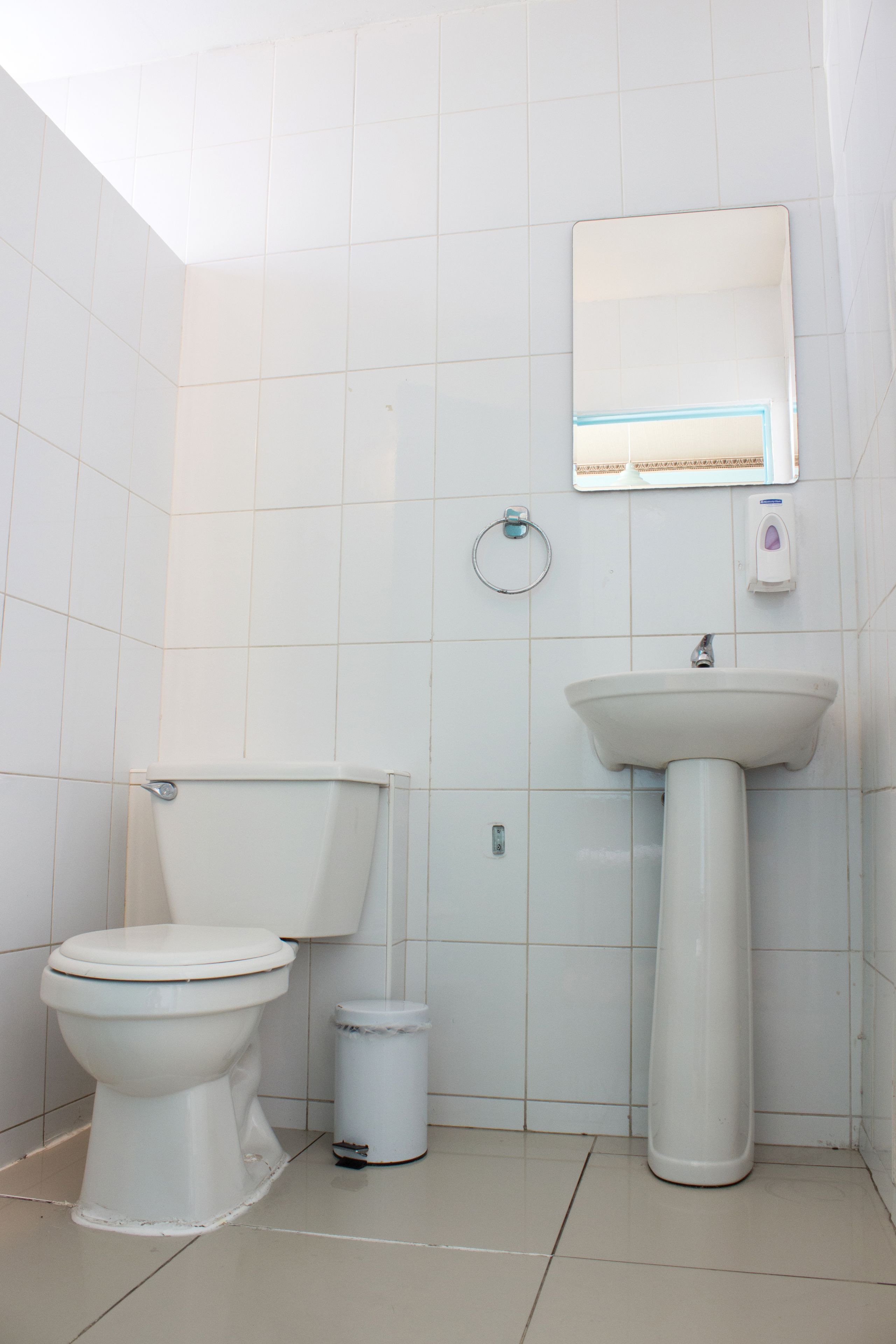 Et badeværelse med toilet, vask og spejl.