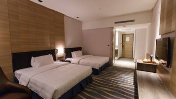 A hotel room with two beds, a TV, a desk, and a bathroom door.