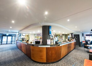 A hotel reception area with a curved counter, a large pillar, and a view of the lobby.